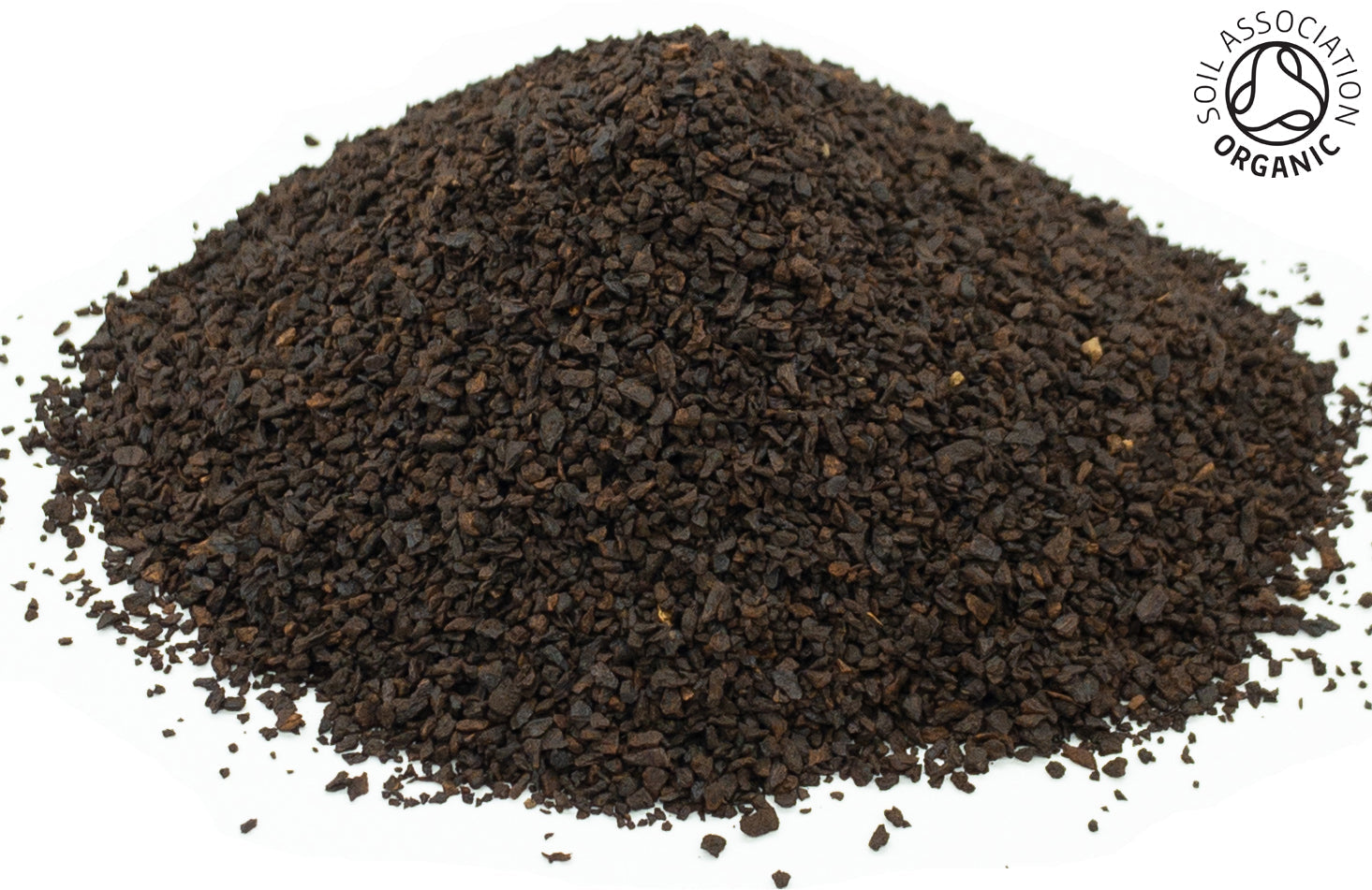 A small pile of dried, roasted, cut, organic chicory root on a white background with the Soil Association Organic Logo in the top right corner