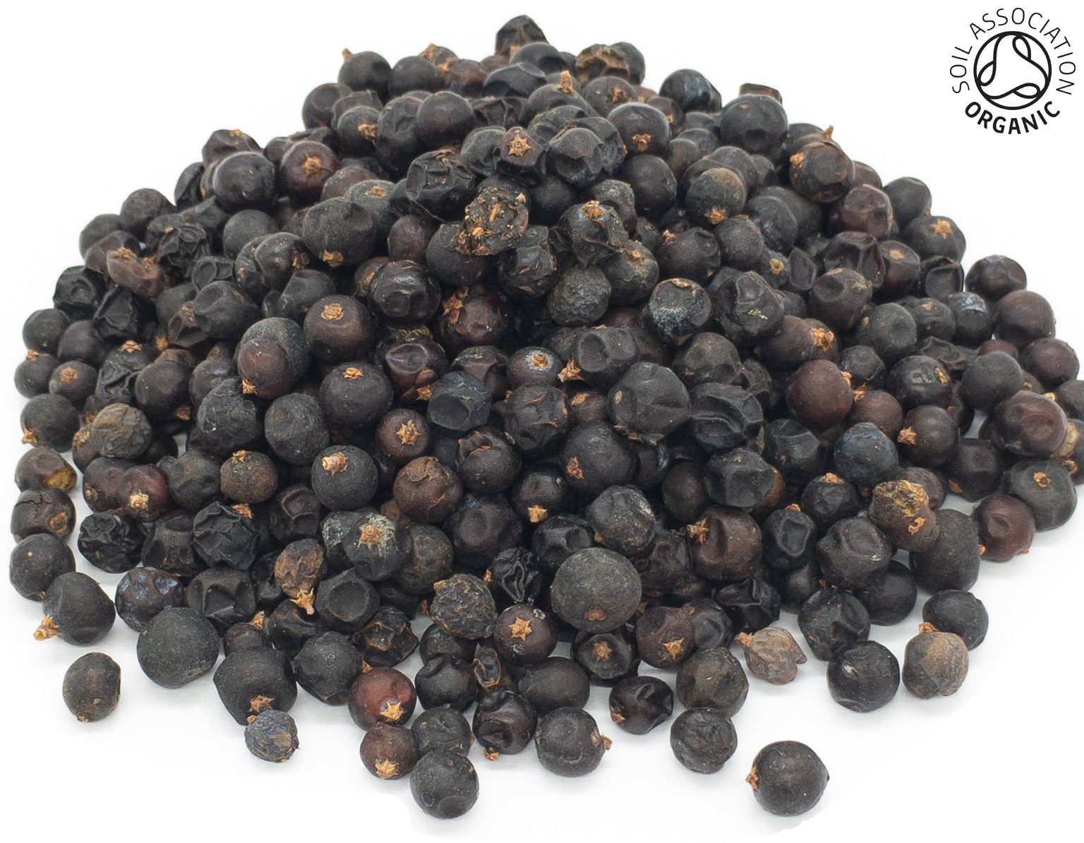 A small pile of dried, organic juniper berries, on a white background with the Soil Association Organic Logo in the top right corner