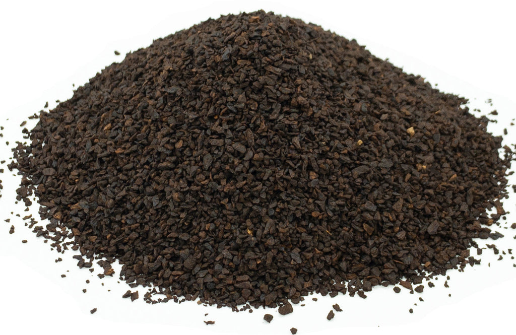 A mound of dark roasted chicory root granules on a white background
