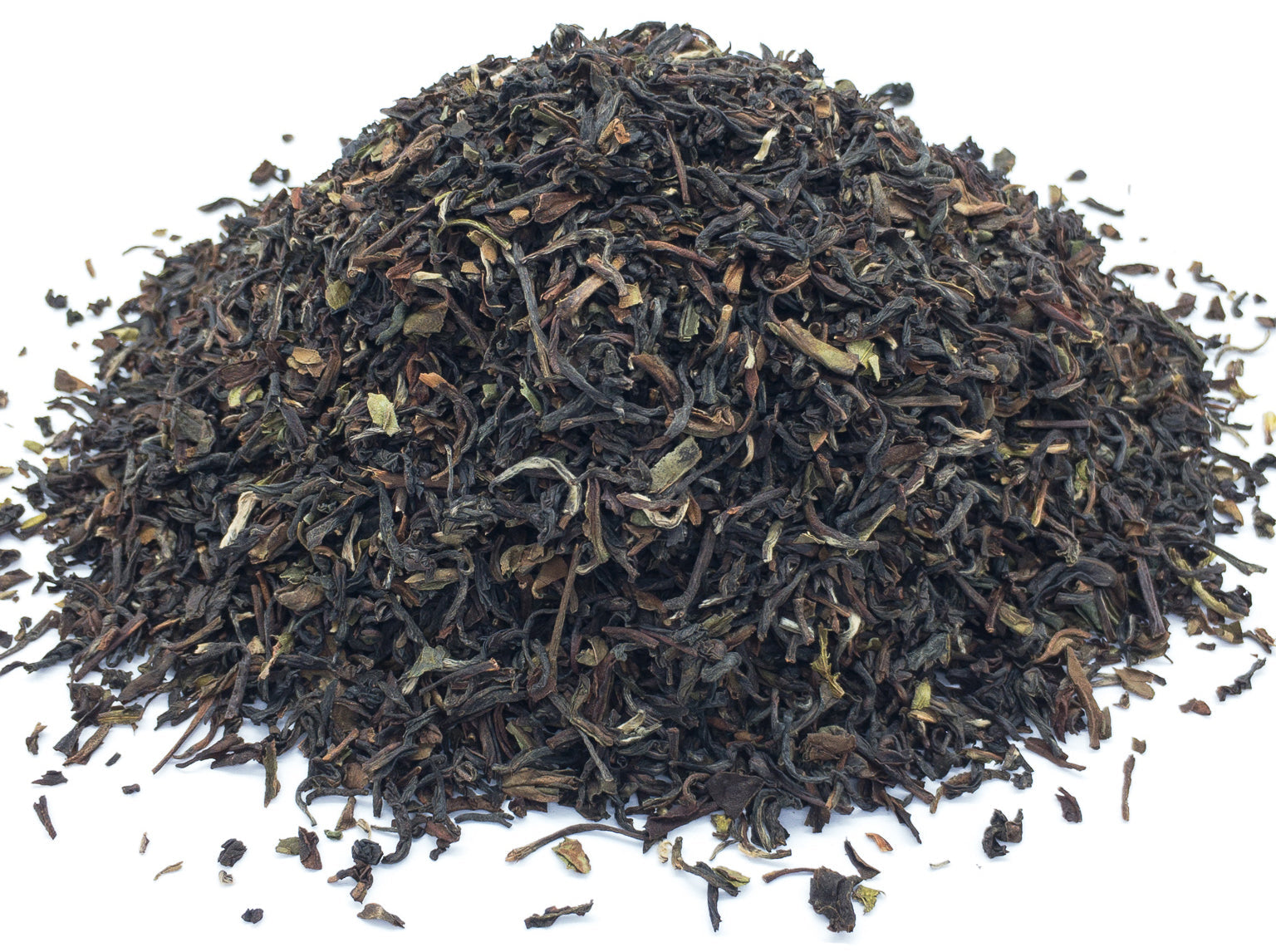 A small pile of dried darjeeling black tea leaves on a white background