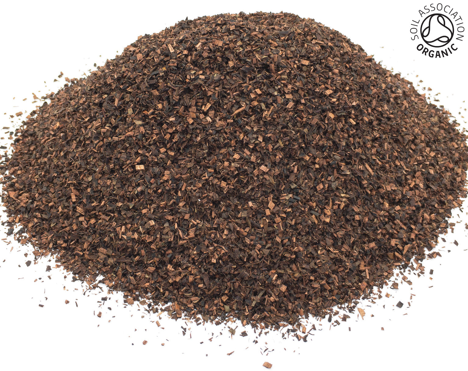 A small pile of dried, cut, organic honeybush leaves, on a white background, with the Soil Association organic logo in the top right hand corner