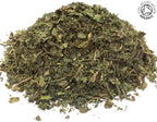 Small pile of dried, cut, organic green stinging nettle leaves on a white background with the Soil Association Organic Logo in the top right corner